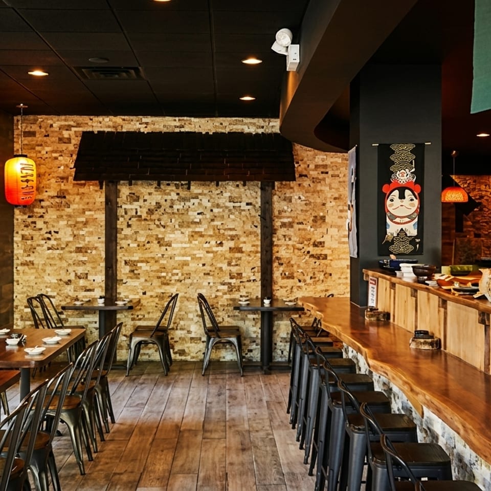 Interior of a Japanese restaurant with wooden tables, bar seating, and traditional decor.